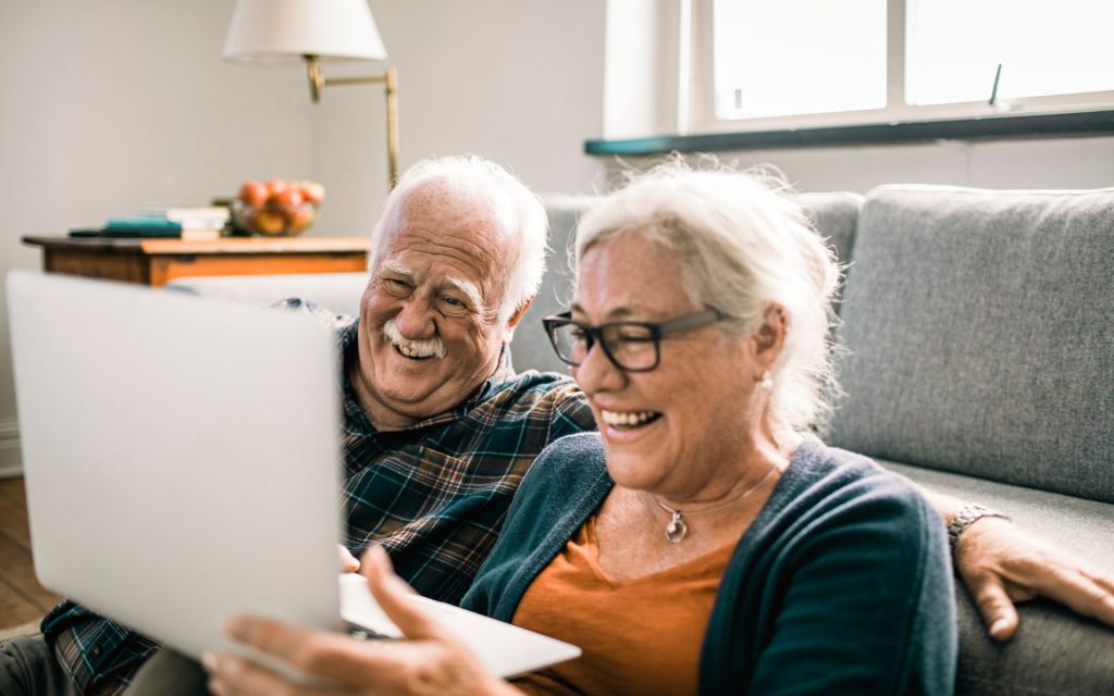 Two seniors laughing at the laptop