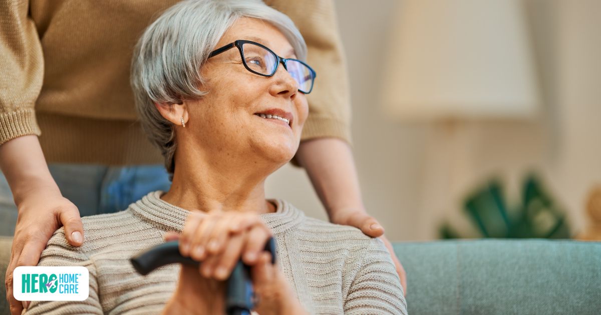 Staying at home vs a long-term care facility, showing an older woman receiving supportive in-home care in a familiar living space