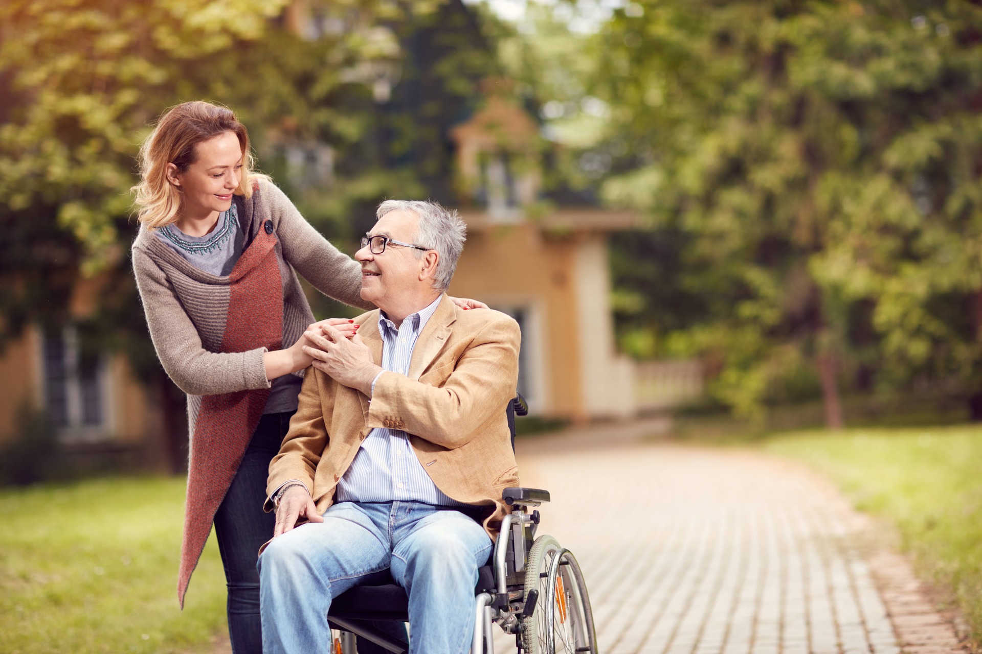 Image of a caregiver touching shoulders of a senior in a wheelchair.