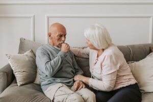 Man Coughing in Gray Sweater Sitting Beside Woman