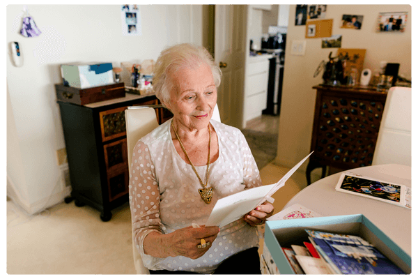 elderly woman sitting at a table looking at a card