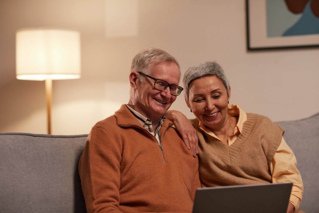 Image of two happy seniors staring at laptop