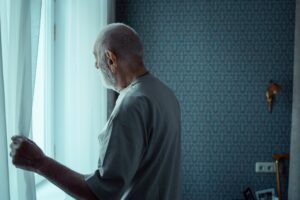 An Elderly Man Opening a Window Curtain