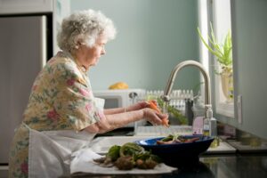 Elderly woman cleaning vegetables.