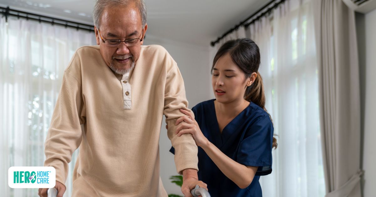 A caregiver gently assisting an older man with walking, showing when extra support at home may be needed.