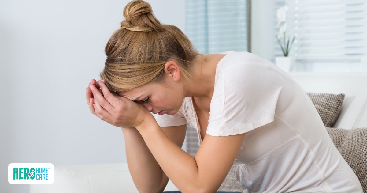 Caregiver sitting with head in hands, showing emotional exhaustion and common signs of caregiver stress.