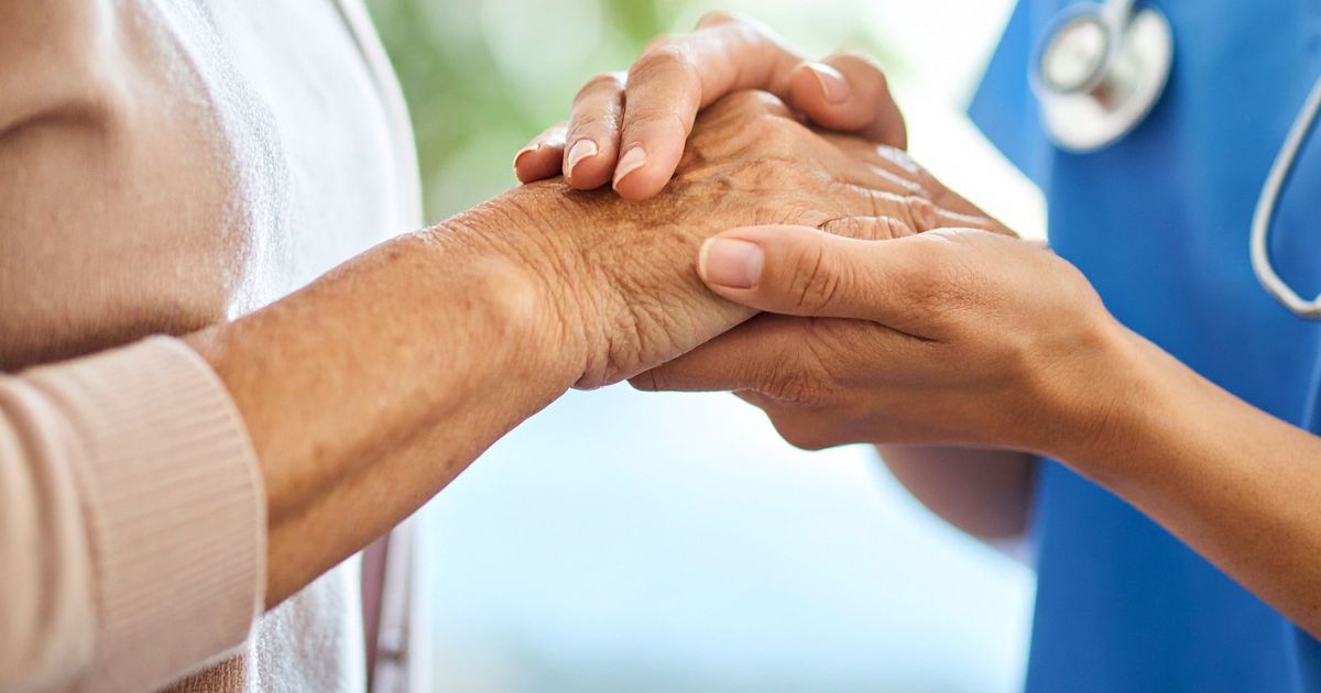 A professional caregiver gently holding an older adult&rsquo;s hands, illustrating what to expect from a professional caregiver.