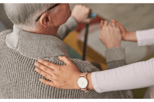 Image of a hand on a seniors back.