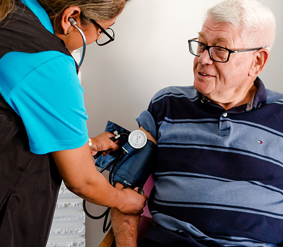 A woman is taking the blood pressure of an elderly man