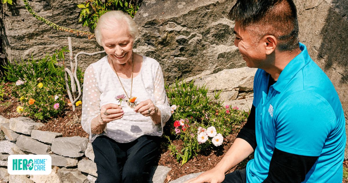 Hero Home Care caregiver sitting outdoors with elderly woman, showing how Hero Home Care helps families