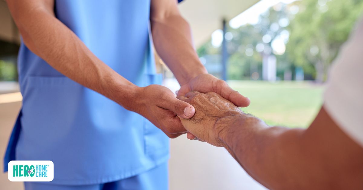 Caregiver holding senior&rsquo;s hand while coordinating local support during long-distance caregiving.