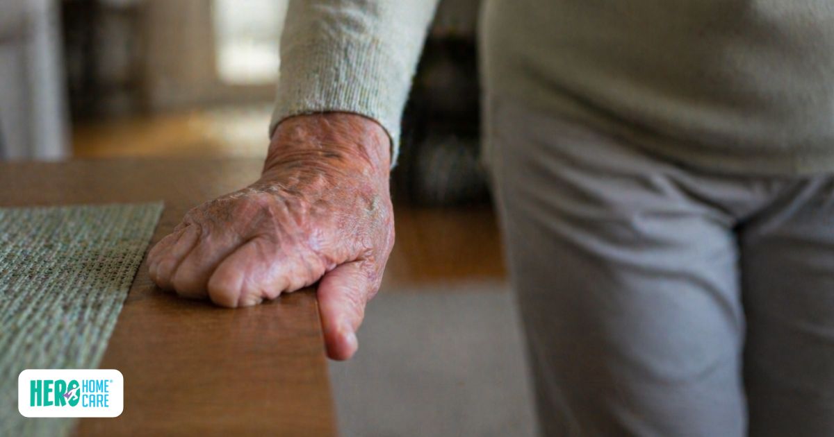 Older adult steadying themselves on a table, indicating signs aging parent&rsquo;s home may not be safe