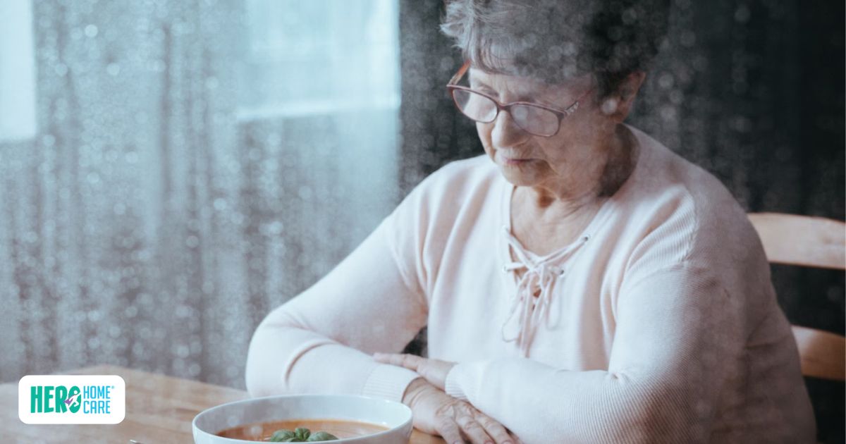 Senior woman with glasses sitting at a wooden table looking down thoughtfully