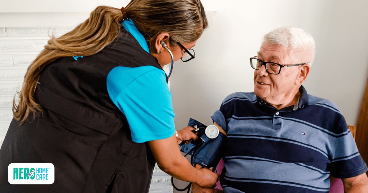 A professional caregiver from Hero Home Care checking a senior man's blood pressure at home, demonstrating how Hero Home Care supports post-hospital care.