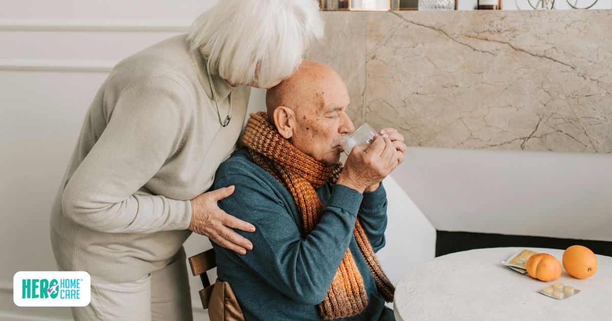A senior man wearing a warm scarf drinking water with a caregiver nearby, highlighting essential nutrition and hydration needs for post-hospital recovery at home.
