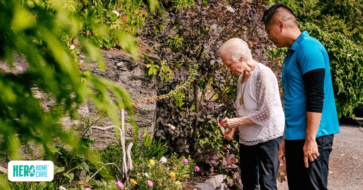 Hero Home Care caregiver accompanying an older adult on a walk through a garden as part of a personalized senior care plan that supports safe, independent aging at home.
